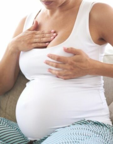 Woman massaging breast for breast tenderness during pregnancy