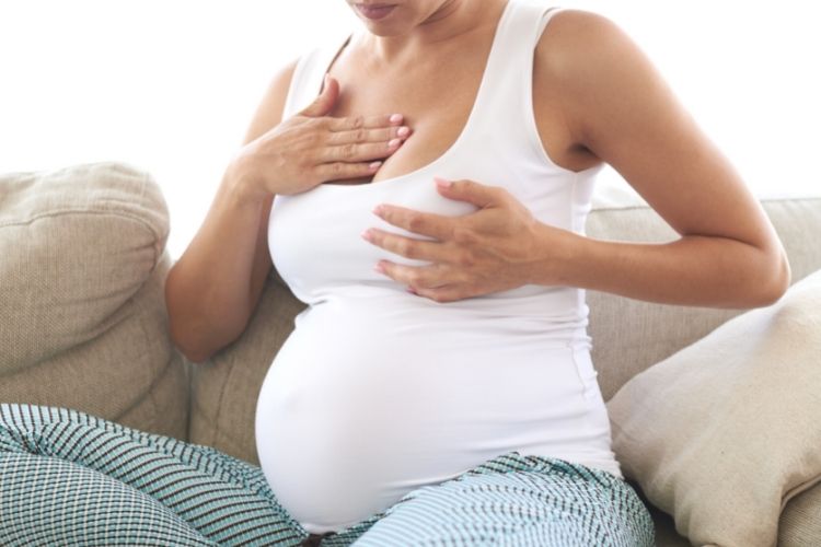 Woman massaging breast for breast tenderness during pregnancy
