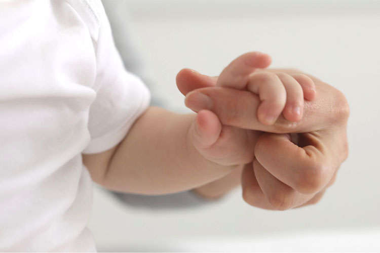 Child holding hand from mama close up
