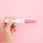 positiver Schwangerschaftstest auf rosa Hintergrund